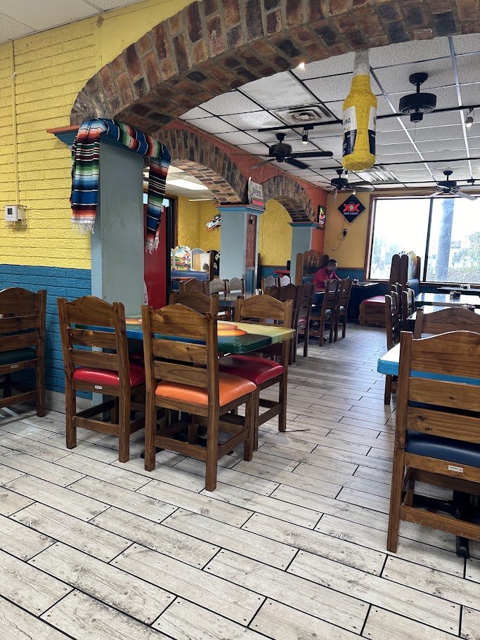 Mexican restaurant interior with tables and warm lighting.